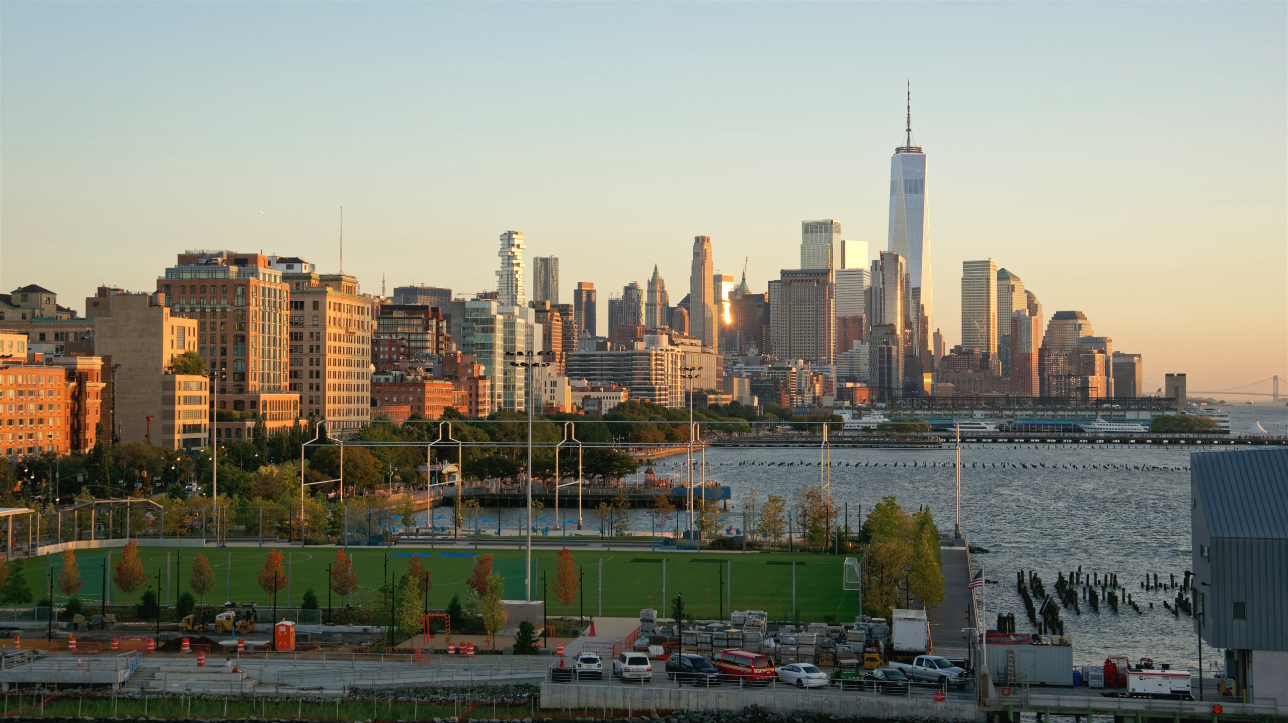 Panoramic Lower Manhattan skyline and One World Trade Center at golden hour across New York Harbor